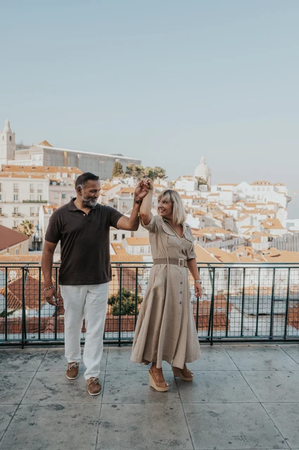 A hand-in-hand turn at the viewpoint | Lisbon couple photoshoot The couple raising their joined hands as she turns beside the viewpoint railing during their couple photoshoot in Lisbon.