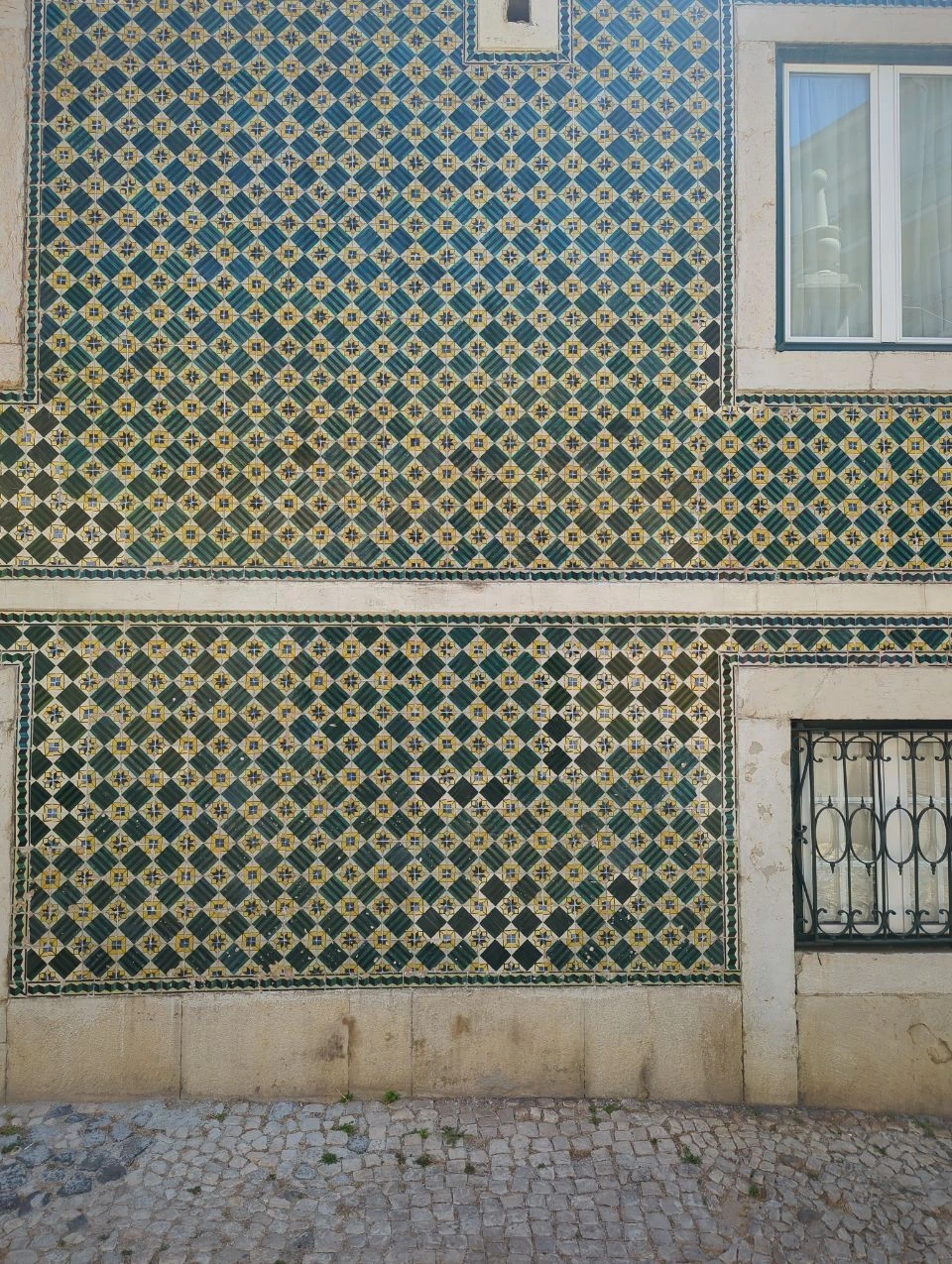 Lisbon Midday Photoshoot - Patterned Tiles Green, blue and yellow patterned tiles cover a Lisbon façade beside stone-framed windows, adding colour to a midday photoshoot route.