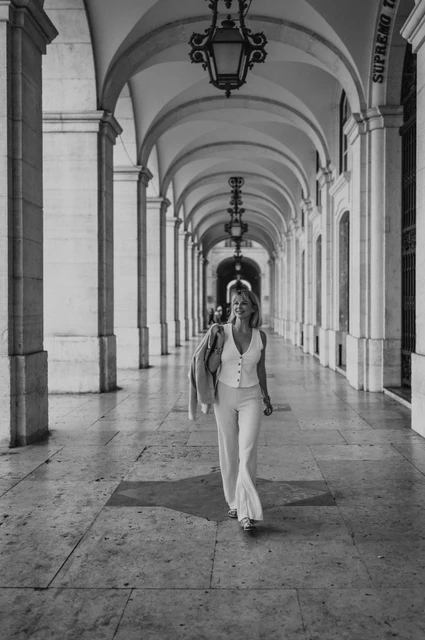The Praça do Comércio arcade in black and white | Lisbon solo photoshoot A black-and-white portrait of the woman walking beneath the arcade at Praça do Comércio during her solo photoshoot in Lisbon.