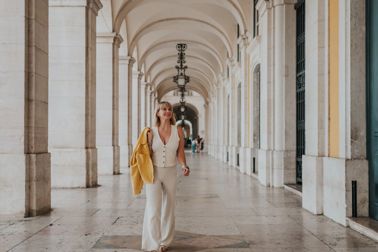 A smile beneath the Praça do Comércio arches | Lisbon solo photoshoot The woman smiling as she walks towards the camera beneath the Praça do Comércio arcade during her solo photoshoot in Lisbon.