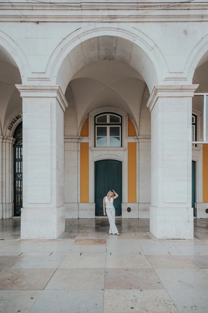 Looking up beneath the stone arch | Lisbon solo photoshoot The woman looking upwards beneath the large stone arch at Praça do Comércio during her solo photoshoot in Lisbon.