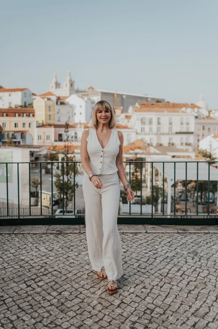 A full-length portrait at Portas do Sol | Lisbon solo photoshoot A full-length portrait of the smiling woman in a cream outfit at Portas do Sol during her solo photoshoot in Lisbon.