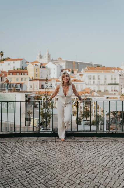 A smile above the Alfama rooftops | Lisbon solo photoshoot The woman leaning towards the camera and smiling at Portas do Sol during her solo photoshoot in Lisbon.