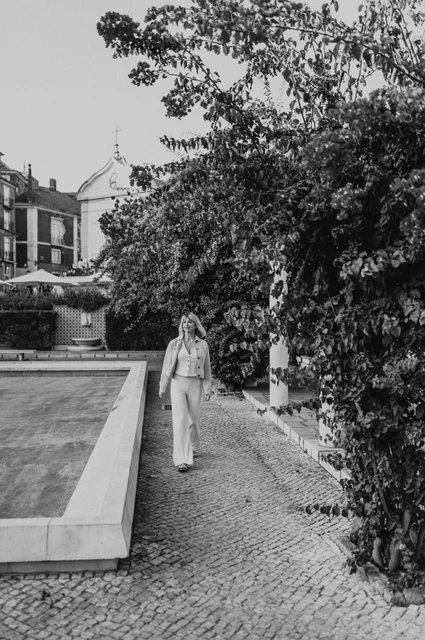 A garden walk in black and white | Lisbon solo photoshoot A black-and-white photograph of the woman walking beside flowers at Santa Luzia during her solo photoshoot in Lisbon.