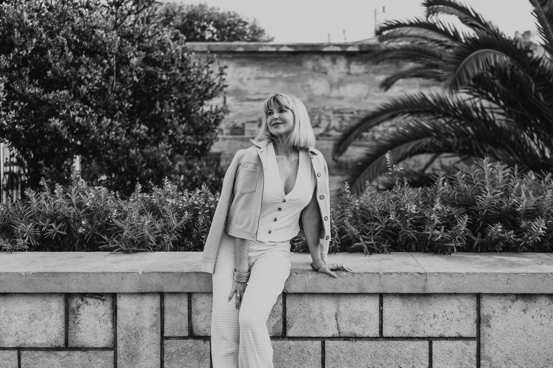 A black-and-white portrait of the woman leaning against the garden wall at Santa Luzia during her solo photoshoot in Lisbon.