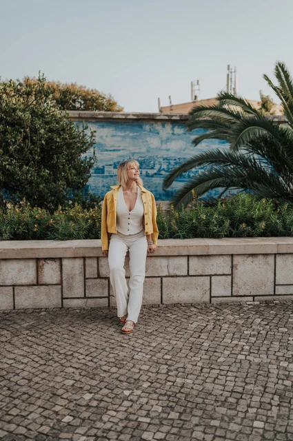 Beside the Santa Luzia garden wall | Lisbon solo photoshoot The woman standing beside a low garden wall with blue tiles and palms at Santa Luzia during her solo photoshoot in Lisbon.