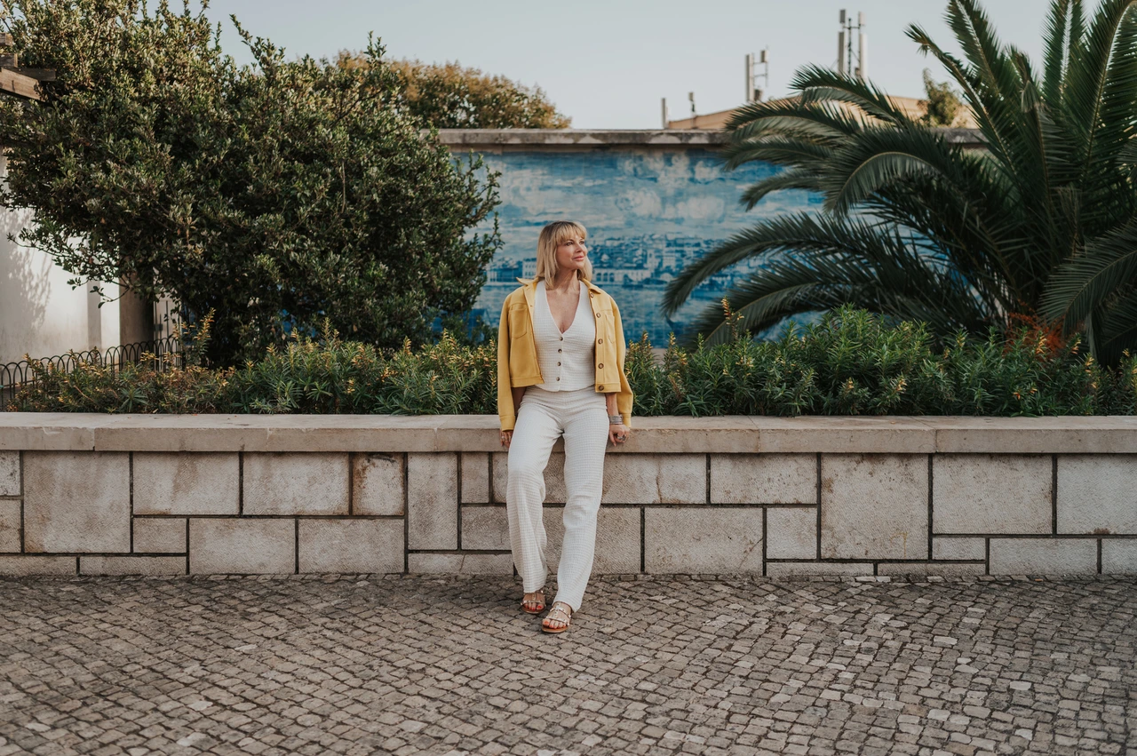 A wide garden portrait at Santa Luzia | Lisbon solo photoshoot A wide portrait of the woman leaning against the garden wall beneath blue tiles and palms at Santa Luzia during her solo photoshoot in Lisbon.