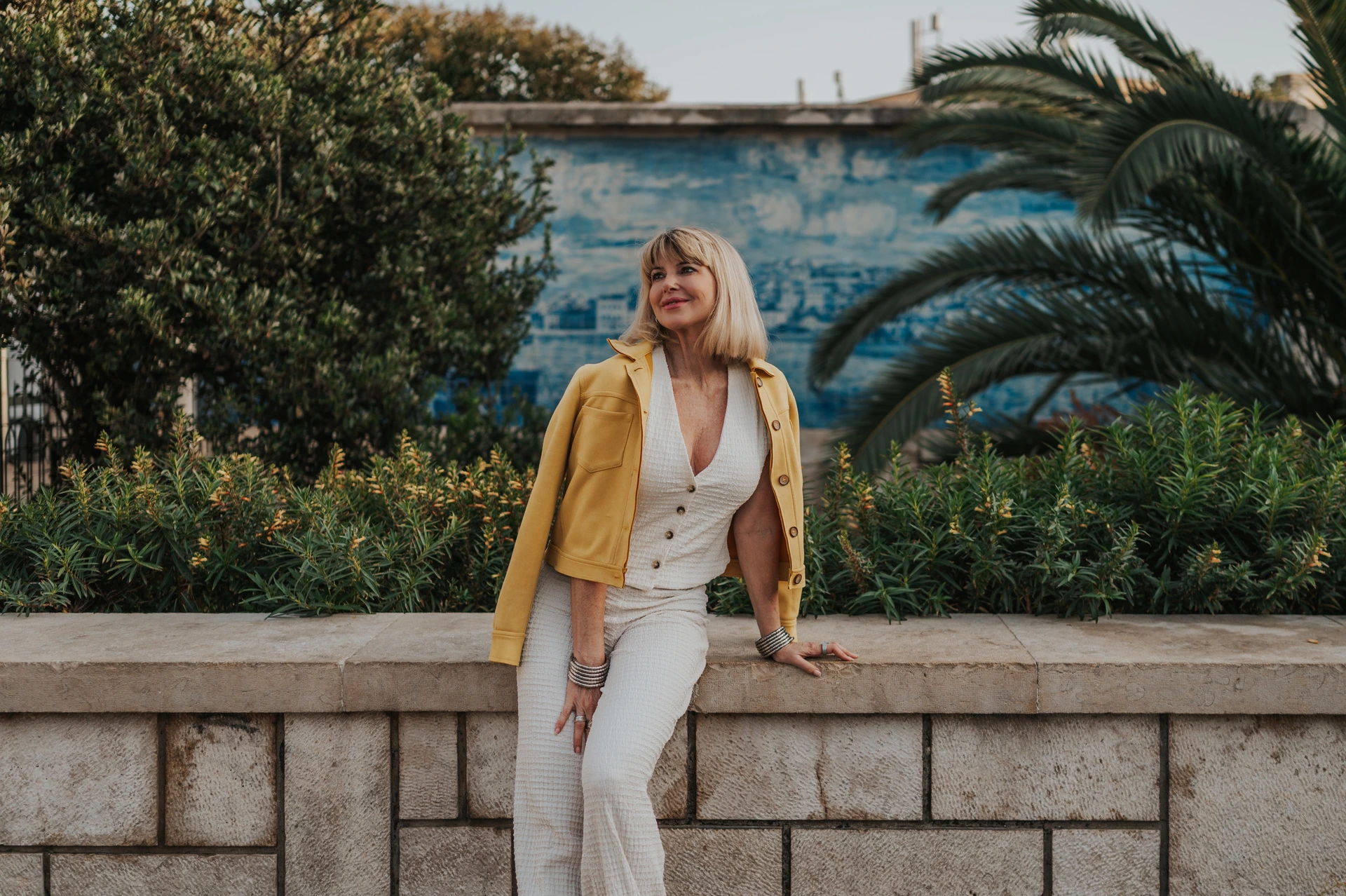 A close portrait beside Santa Luzia’s tiles | Lisbon solo photoshoot The woman looking to the side with her yellow jacket over her shoulder beside the garden wall at Santa Luzia during her solo photoshoot in Lisbon.
