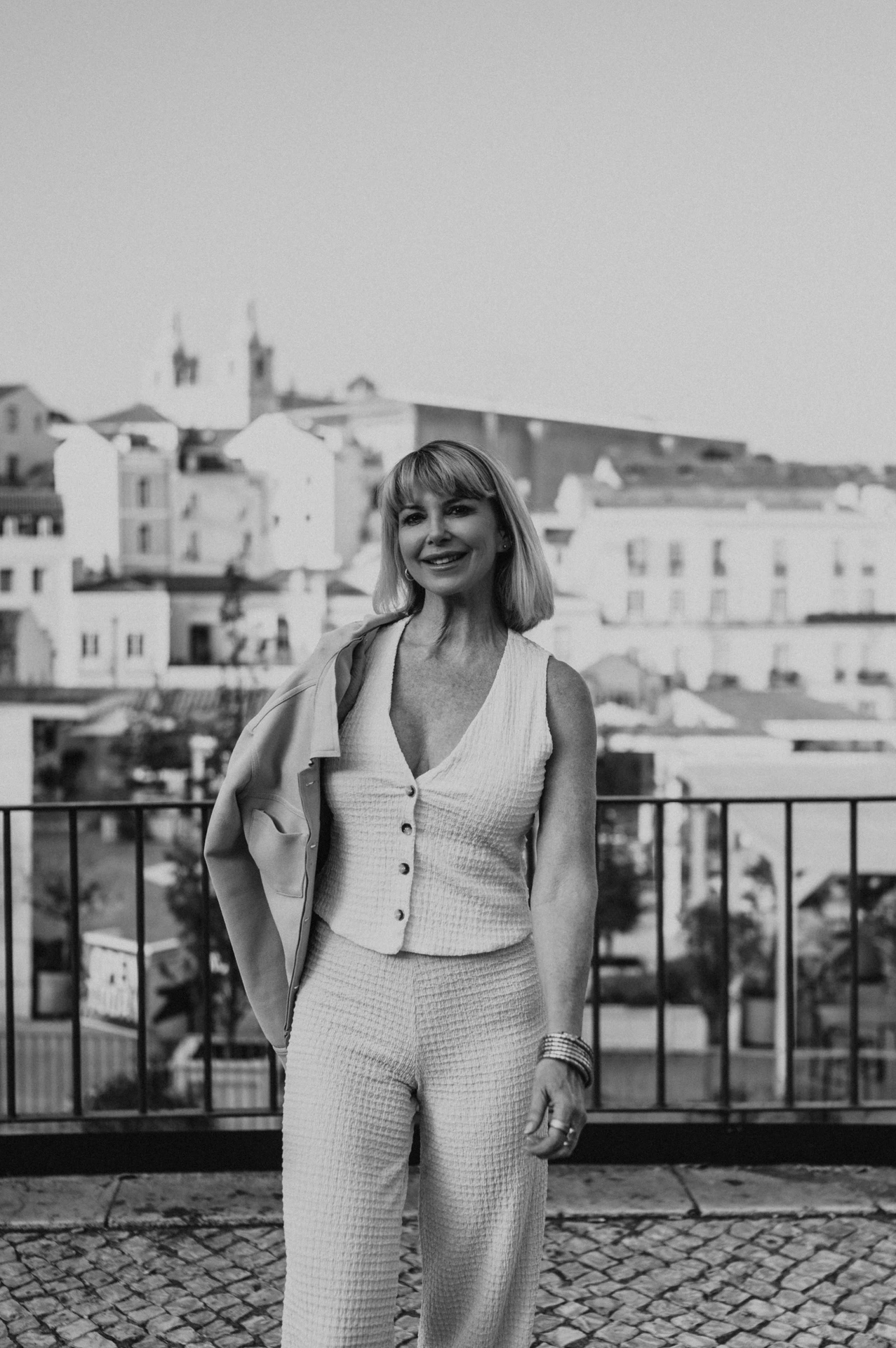 A black-and-white portrait of the woman with her jacket over one shoulder at Portas do Sol during her solo photoshoot in Lisbon.