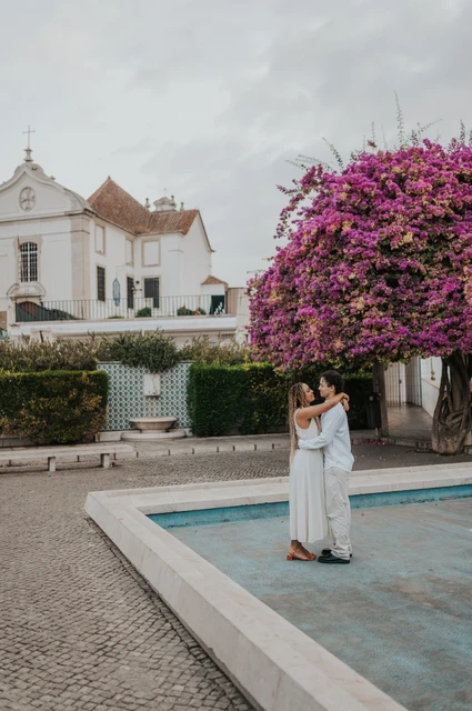 An embrace beside the garden pool | Lisbon couple photoshoot The couple embracing beside the shallow garden pool and flowering branches during their couple photoshoot in Lisbon.