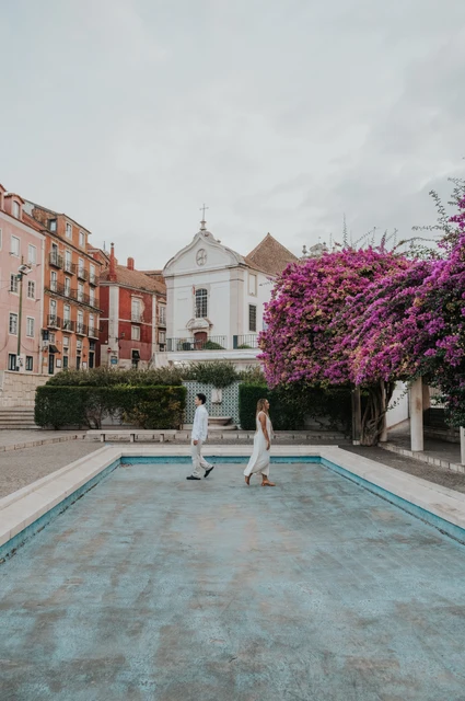 A hand-in-hand moment beside the garden pool | Lisbon couple photoshoot The couple facing each other across the paved edge of the garden pool during their couple photoshoot in Lisbon.