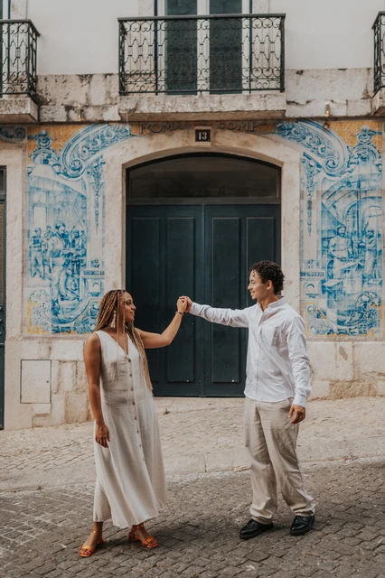 A hand-in-hand turn at the green door | Lisbon couple photoshoot The couple raising their joined hands across the green doorway surrounded by blue tiles during their couple photoshoot in Lisbon.