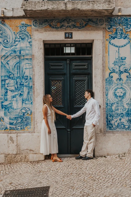 A portrait beside the green tiled doorway | Lisbon couple photoshoot The couple standing on either side of a green doorway framed by blue Portuguese tiles during their couple photoshoot in Lisbon.
