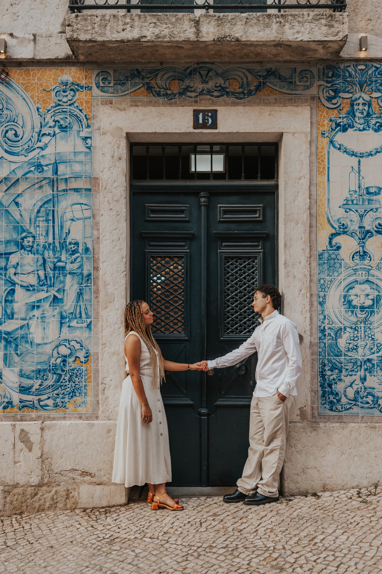 The couple standing on either side of a green doorway framed by blue Portuguese tiles during their couple photoshoot in Lisbon.