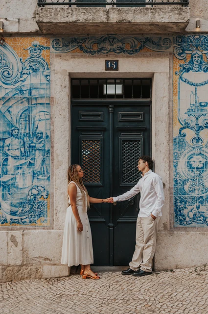 A portrait beside the green tiled doorway | Lisbon couple photoshoot The couple standing on either side of a green doorway framed by blue Portuguese tiles during their couple photoshoot in Lisbon.
