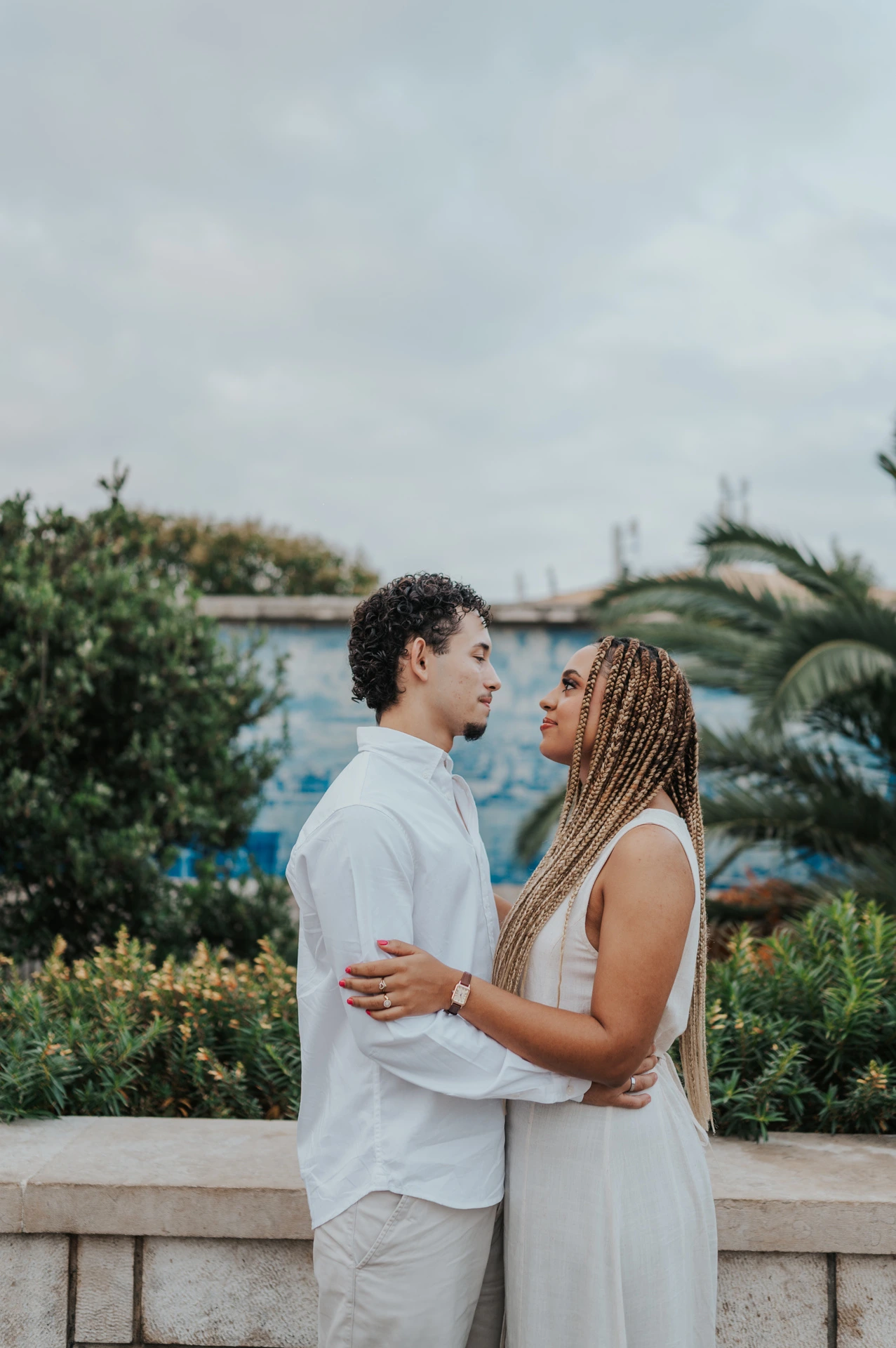 The couple holding each other close beside the palms and blue tiles during their couple photoshoot in Lisbon.