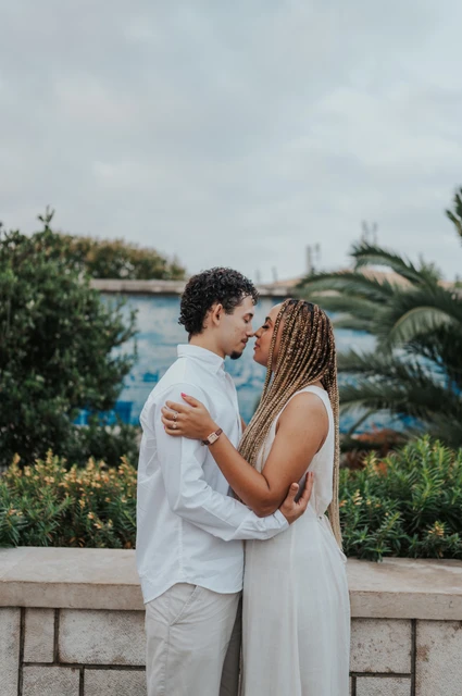 A close embrace at the tiled viewpoint | Lisbon couple photoshoot The couple holding each other close beside the palms and blue tiles during their couple photoshoot in Lisbon.