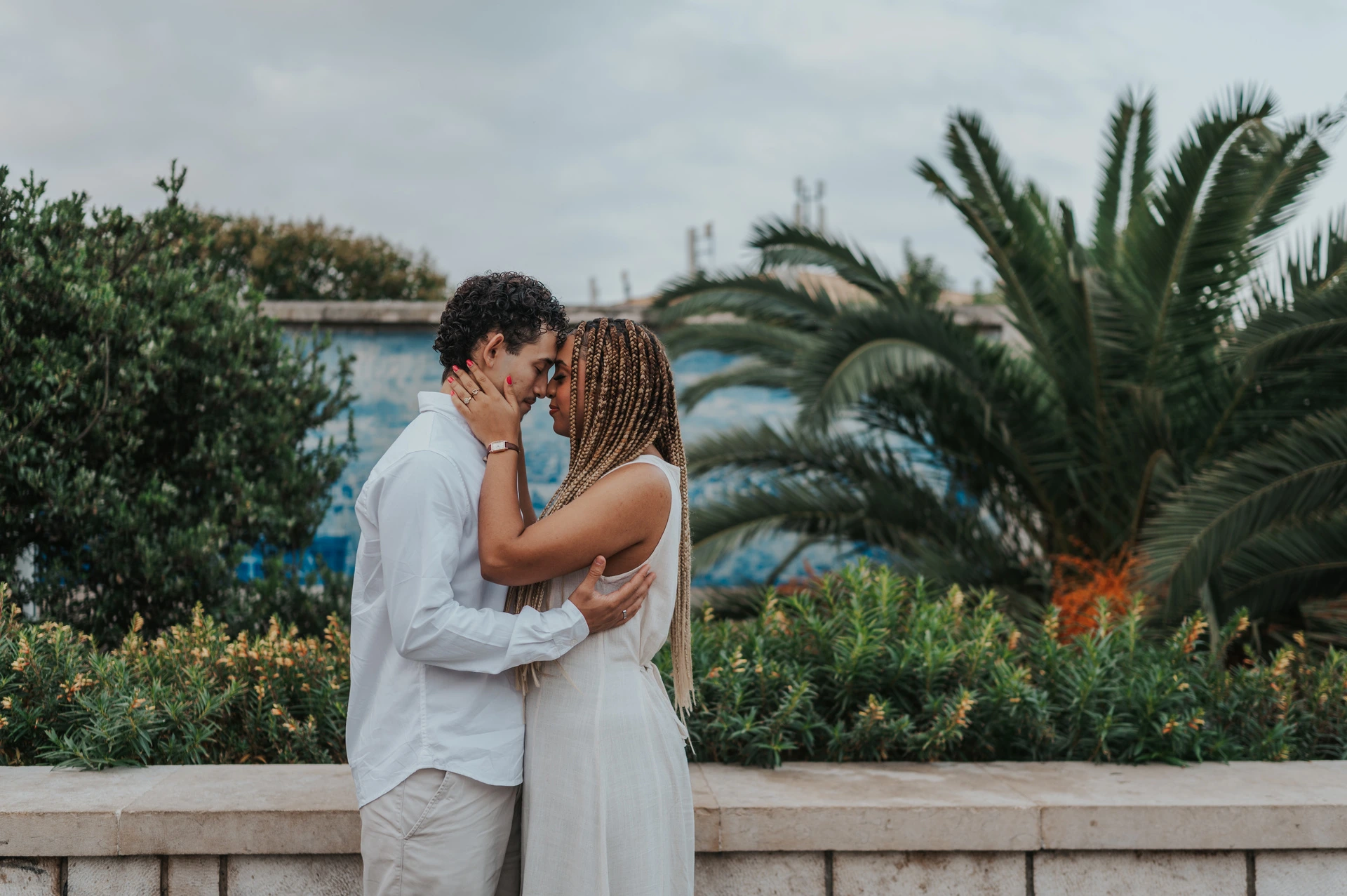 The couple holding each other close beside the palms and blue tiles during their couple photoshoot in Lisbon.