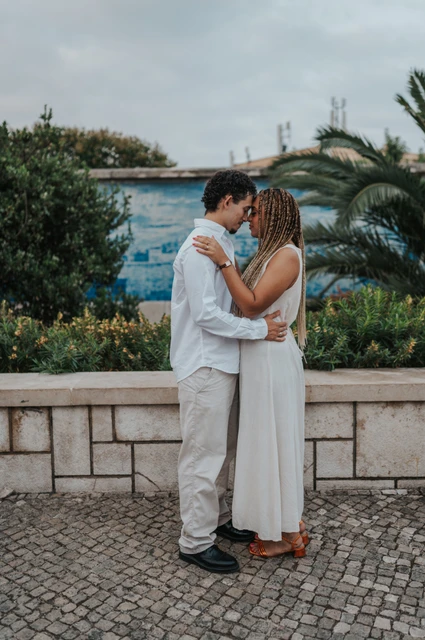 A close embrace at the tiled viewpoint | Lisbon couple photoshoot The couple holding each other close beside the palms and blue tiles during their couple photoshoot in Lisbon.