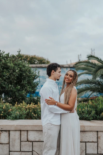 A close embrace at the tiled viewpoint | Lisbon couple photoshoot The couple holding each other close beside the palms and blue tiles during their couple photoshoot in Lisbon.