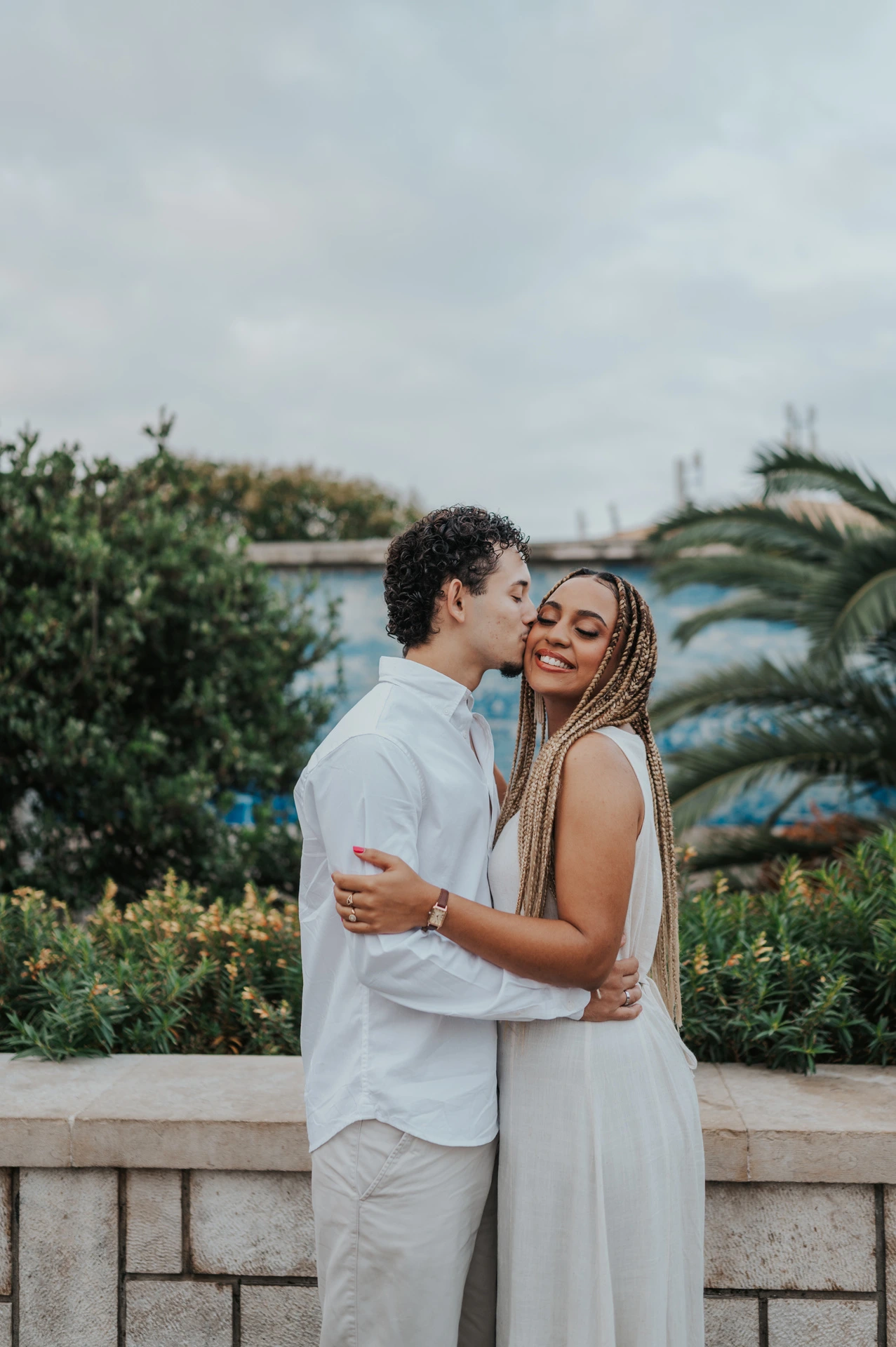 The couple holding each other close beside the palms and blue tiles during their couple photoshoot in Lisbon.