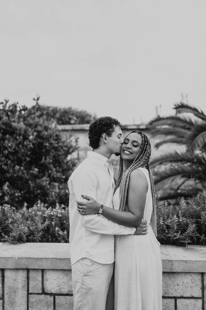 A close embrace at the tiled viewpoint in black and white | Lisbon couple photoshoot Black-and-white photograph: the couple holding each other close beside the palms and blue tiles during their couple photoshoot in Lisbon.