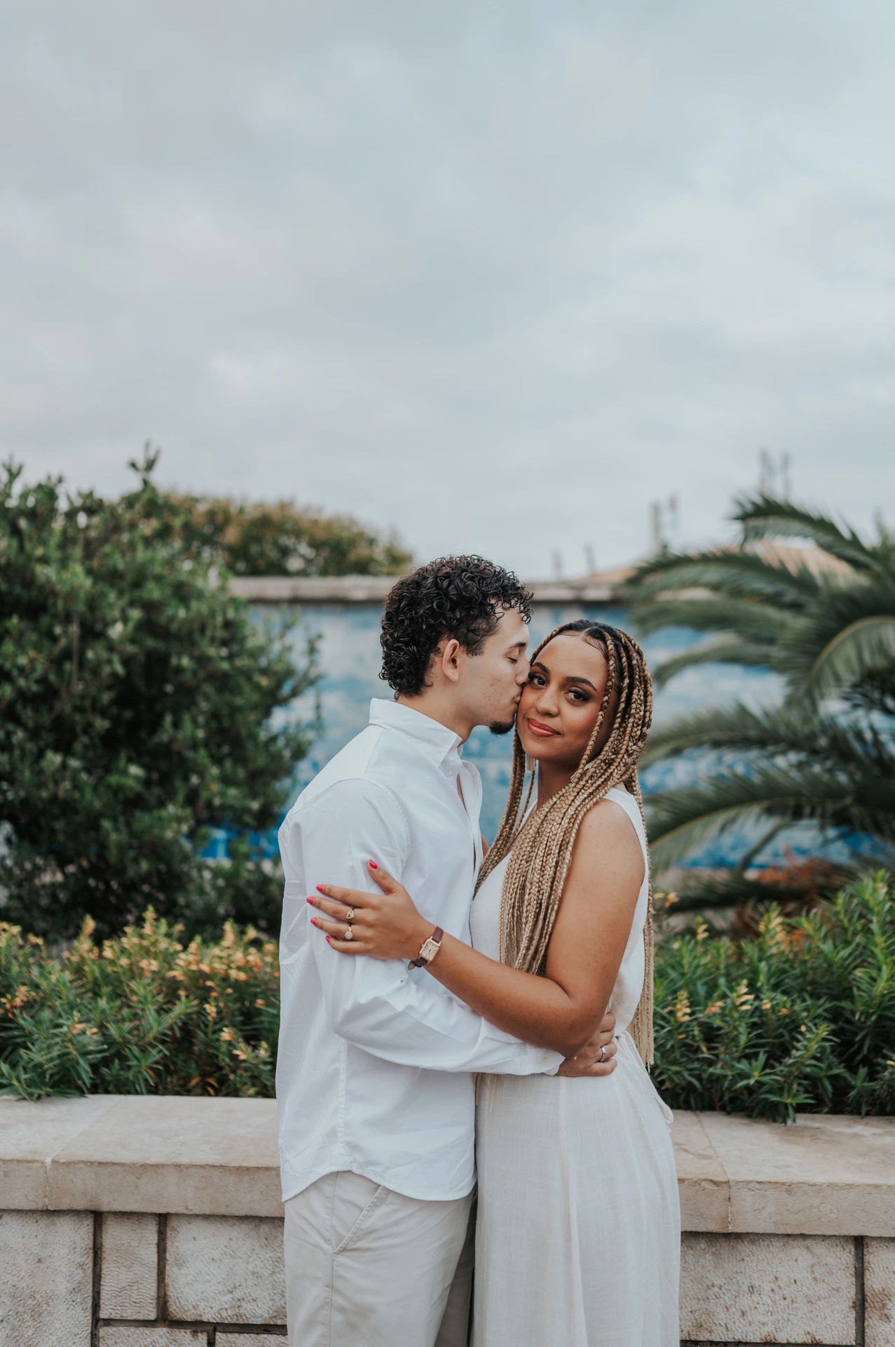 The couple holding each other close beside the palms and blue tiles during their couple photoshoot in Lisbon.