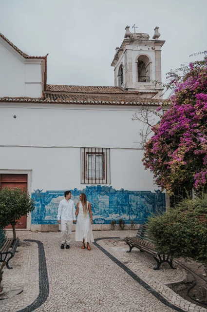 A walk beside Igreja de Santa Luzia | Lisbon couple photoshoot The couple holding hands along the garden path by Igreja de Santa Luzia and its blue tile panels during their couple photoshoot in Lisbon.