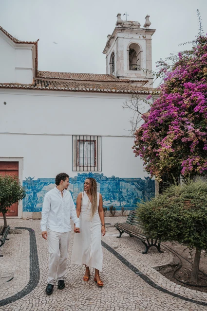 A walk beside Igreja de Santa Luzia | Lisbon couple photoshoot The couple holding hands along the garden path by Igreja de Santa Luzia and its blue tile panels during their couple photoshoot in Lisbon.