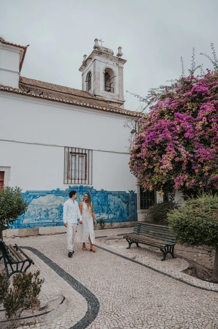 A walk beside Igreja de Santa Luzia | Lisbon couple photoshoot The couple holding hands along the garden path by Igreja de Santa Luzia and its blue tile panels during their couple photoshoot in Lisbon.