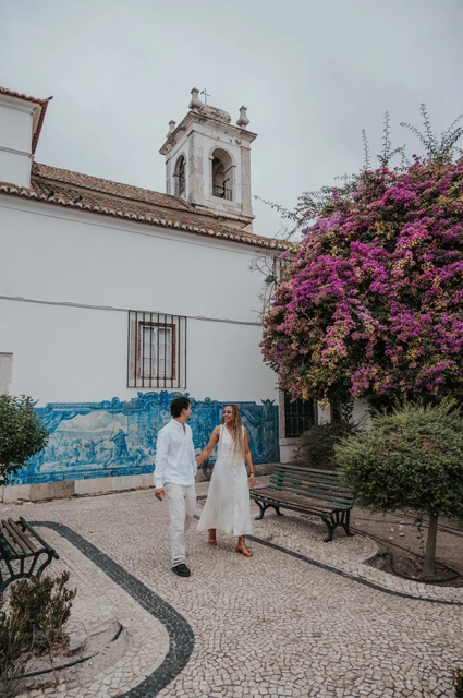 A walk beside Igreja de Santa Luzia | Lisbon couple photoshoot The couple holding hands along the garden path by Igreja de Santa Luzia and its blue tile panels during their couple photoshoot in Lisbon.