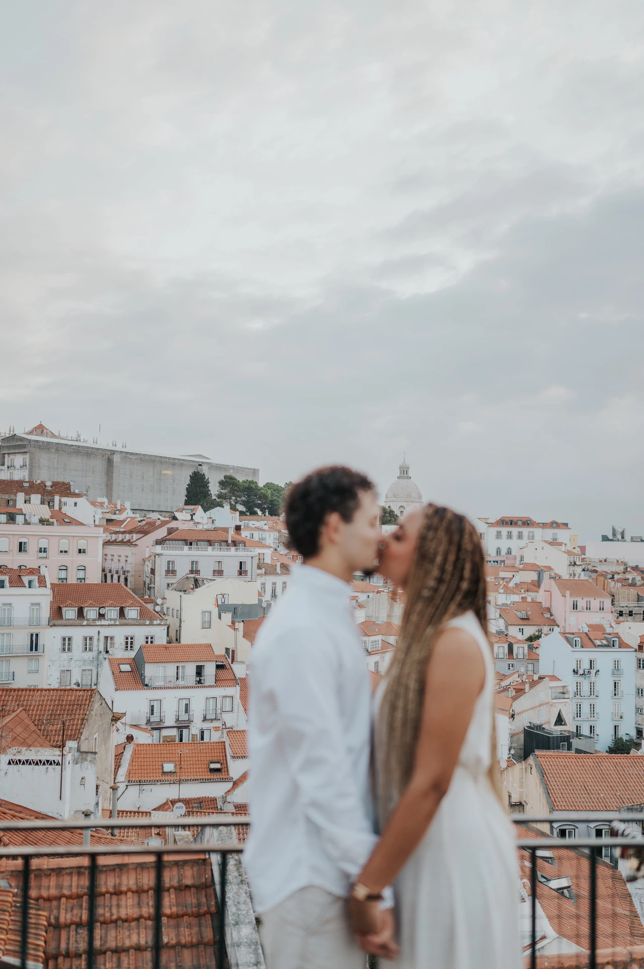 A softly focused portrait of the couple facing each other with Lisbon’s rooftops behind them during their couple photoshoot in Lisbon.