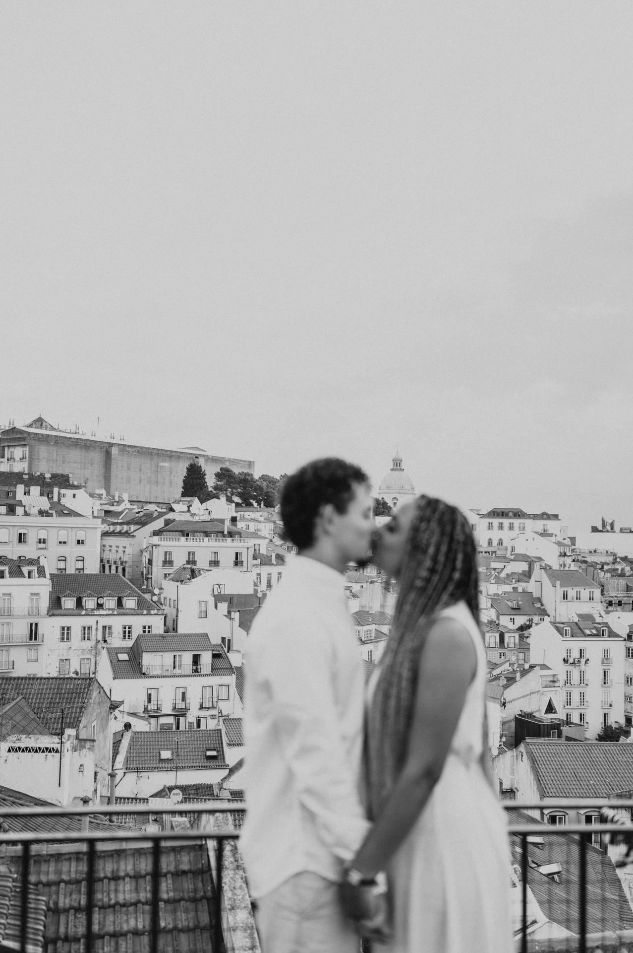 Black-and-white photograph: a softly focused portrait of the couple facing each other with Lisbon’s rooftops behind them during their couple photoshoot in Lisbon.