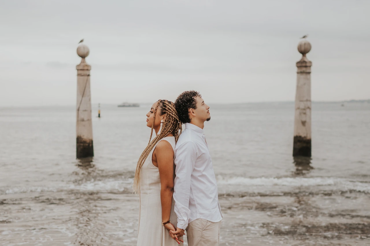 Back to back beside the river | Lisbon couple photoshoot The couple standing back to back on the waterfront steps beside the Tagus River during their couple photoshoot in Lisbon.