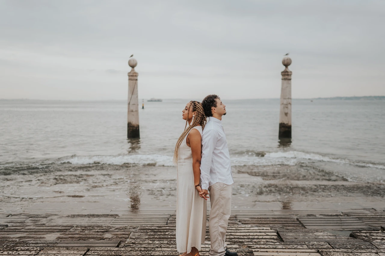 Back to back beside the river | Lisbon couple photoshoot The couple standing back to back on the waterfront steps beside the Tagus River during their couple photoshoot in Lisbon.