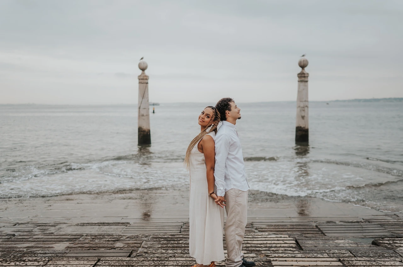 Back to back beside the river | Lisbon couple photoshoot The couple standing back to back on the waterfront steps beside the Tagus River during their couple photoshoot in Lisbon.