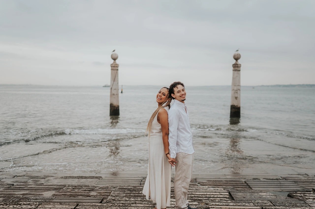 Back to back beside the river | Lisbon couple photoshoot The couple standing back to back on the waterfront steps beside the Tagus River during their couple photoshoot in Lisbon.
