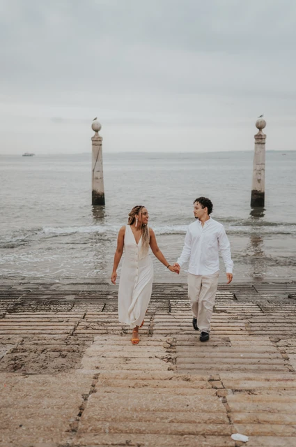 Hand in hand on the waterfront steps | Lisbon couple photoshoot The couple smiling and holding hands as they walk up the stone waterfront steps during their couple photoshoot in Lisbon.