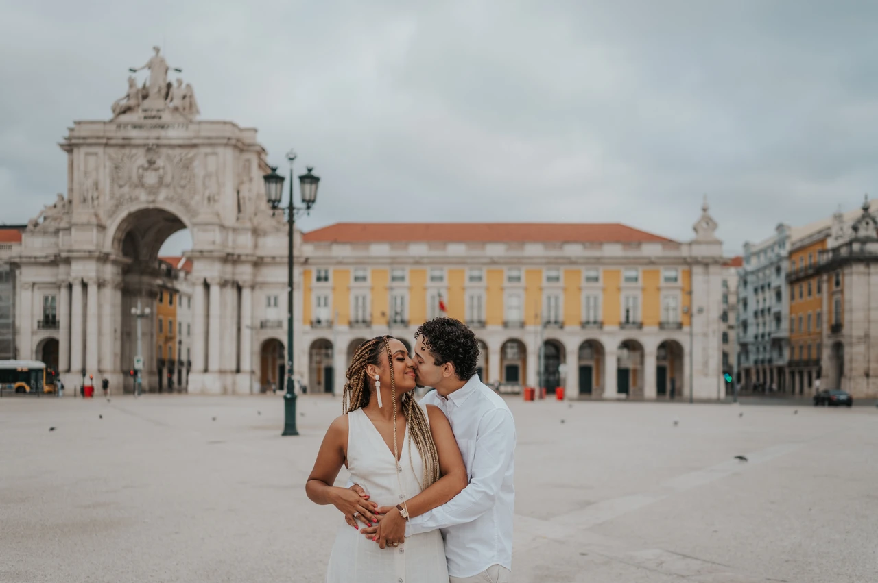 An embrace in Praça do Comércio | Lisbon couple photoshoot The man embracing his smiling partner from behind with Praça do Comércio in the background during their couple photoshoot in Lisbon.