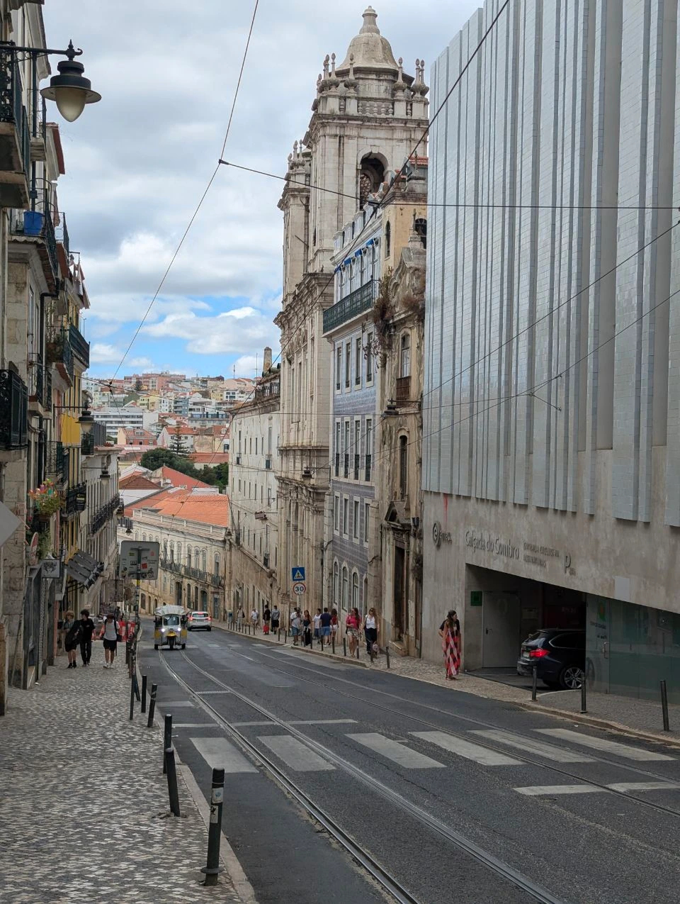 Lisbon Photoshoot Route - Steep Rail Street Tram rails lead down a steep Lisbon street between historic facades, patterned pavements and a church tower.
