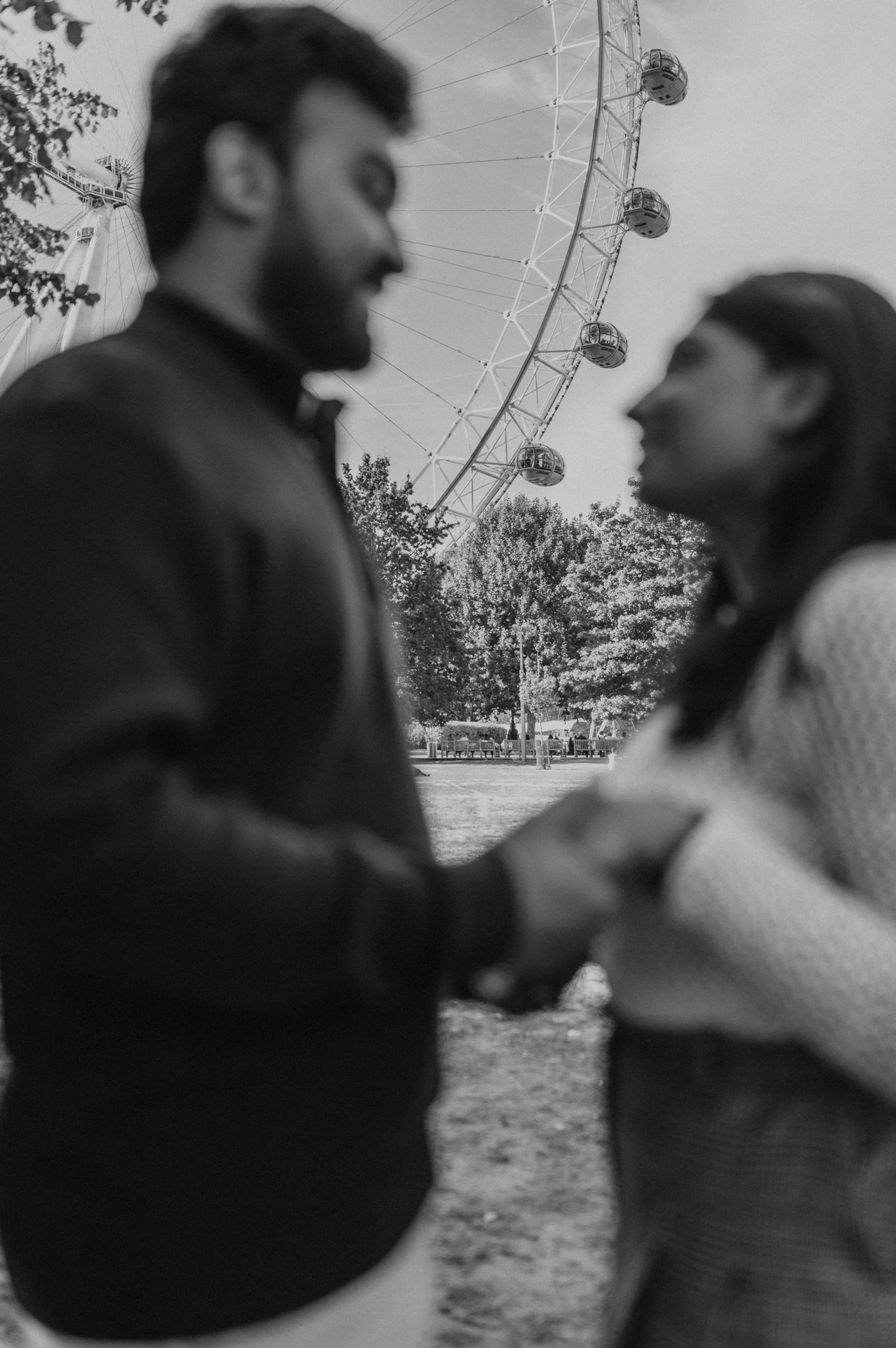 A black-and-white photograph of the softly focused couple facing each other in Jubilee Gardens, with the London Eye visible above them during their London couple photoshoot.