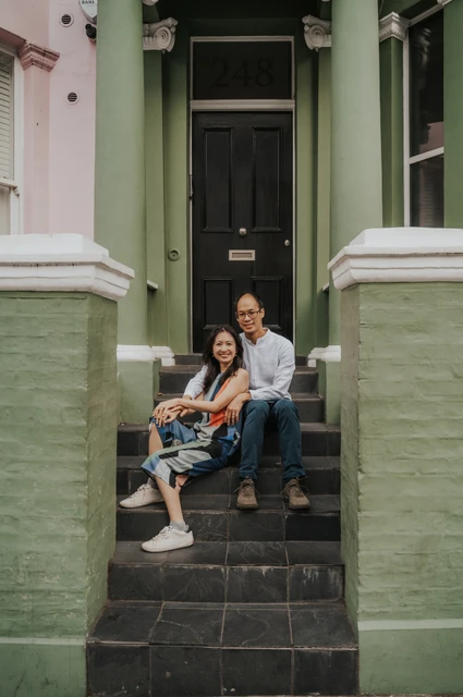 London couple photoshoot: together beneath the green house doorway The couple sit together on the stone staircase beneath the black front door of a green Notting Hill house during their London couple photoshoot.