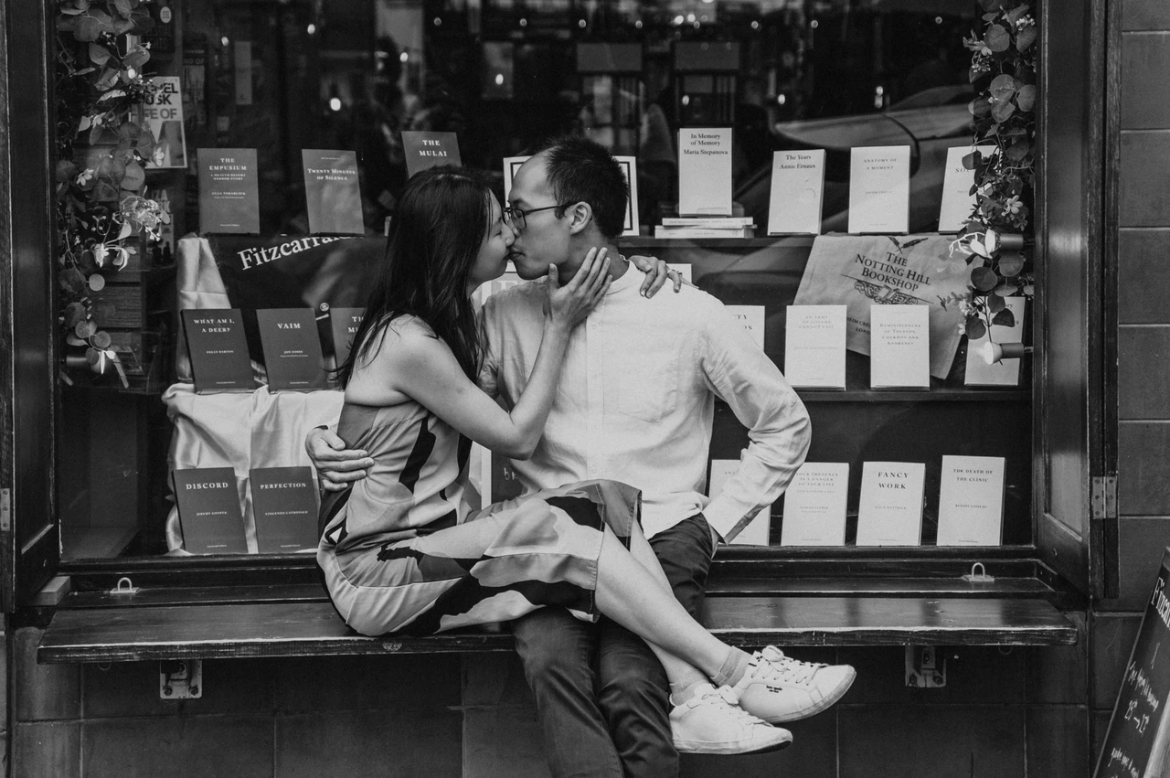 London couple photoshoot: a bookshop bench kiss in black and white A black-and-white close portrait of the couple kissing on the bench outside The Notting Hill Bookshop during their London couple photoshoot.