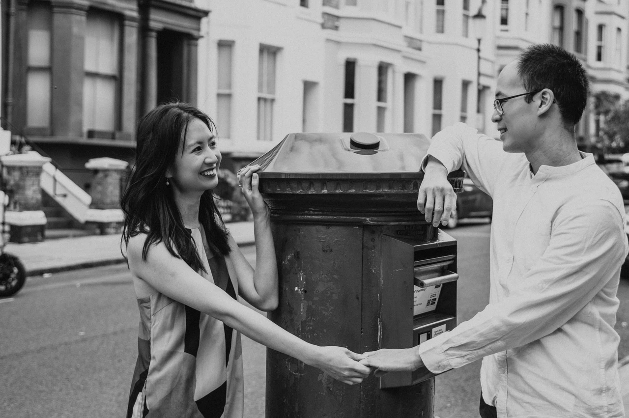 London couple photoshoot: postbox portraits in black and white A black-and-white close portrait of the couple holding hands across a postbox on a Notting Hill street during their London couple photoshoot.
