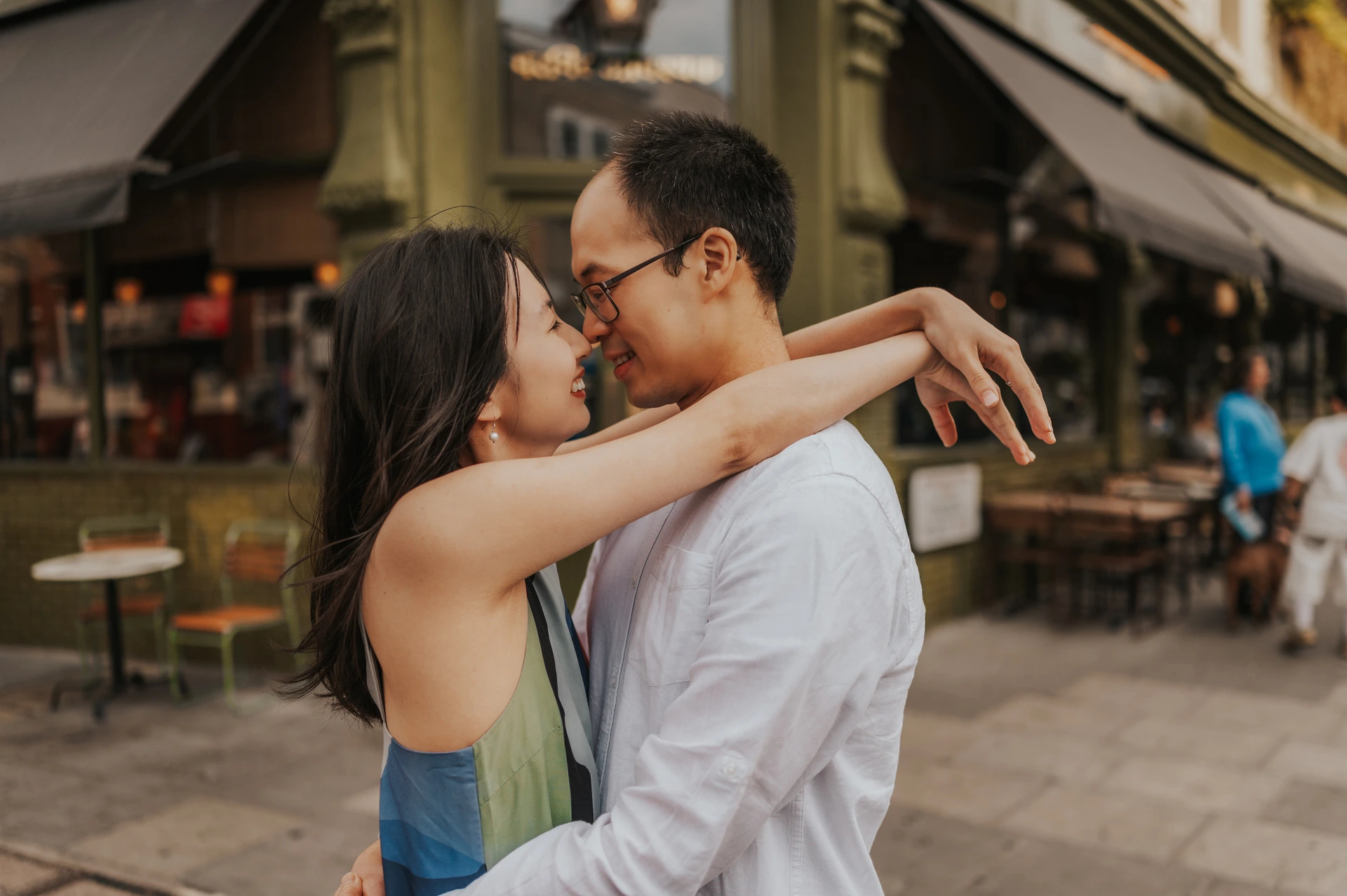 A close landscape portrait of the couple embracing with their faces close together beside a Notting Hill shopfront and awning during their London couple photoshoot.