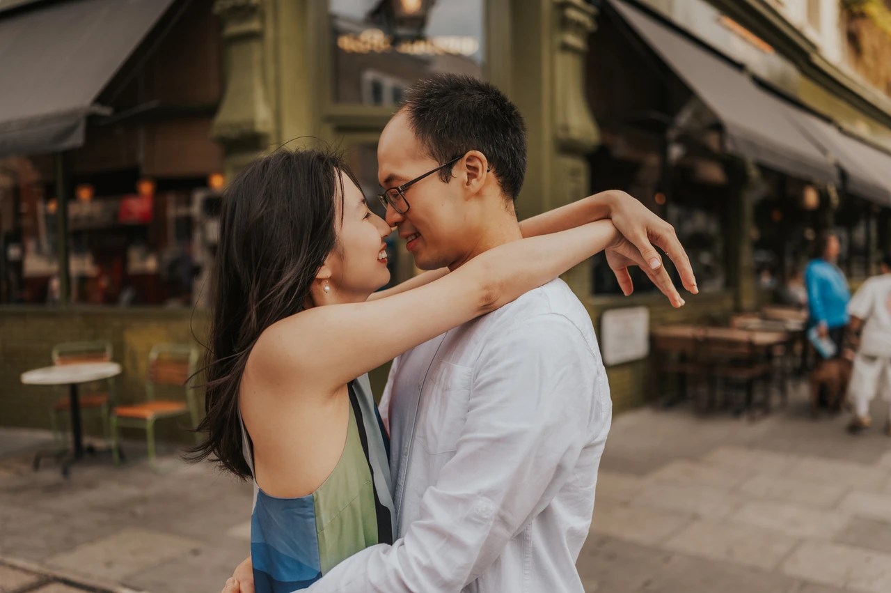 London couple photoshoot: an embrace beside a Notting Hill shopfront A close landscape portrait of the couple embracing with their faces close together beside a Notting Hill shopfront and awning during their London couple photoshoot.