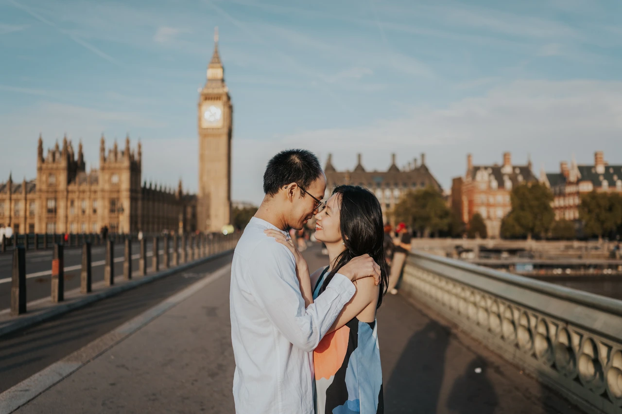 London couple photoshoot kissing on Westminster Bridge Wide portrait of the couple kissing on Westminster Bridge, with Big Ben and the Thames behind them, during their London couple photoshoot.