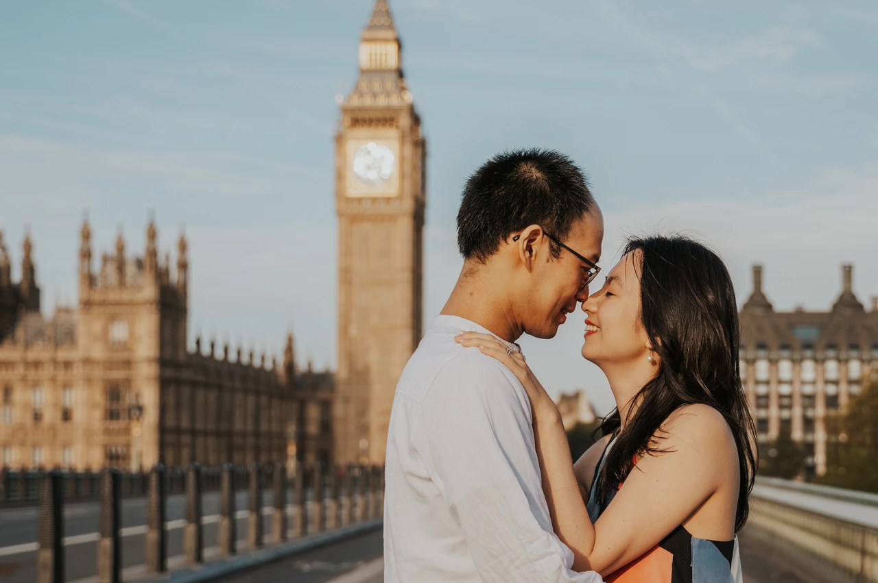 London couple photoshoot smiling together beside Big Ben Close portrait of the couple smiling face to face on Westminster Bridge, with Big Ben in the background, during their London couple photoshoot.