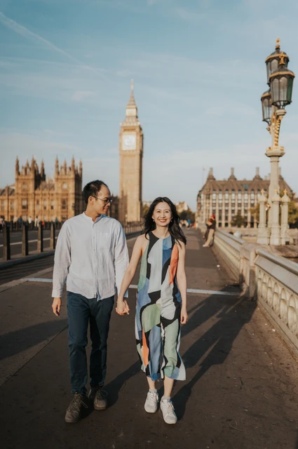London couple photoshoot beside Big Ben and an ornate bridge lamp Couple walking together on Westminster Bridge, with an ornate lamp and Big Ben behind them, during their London couple photoshoot.
