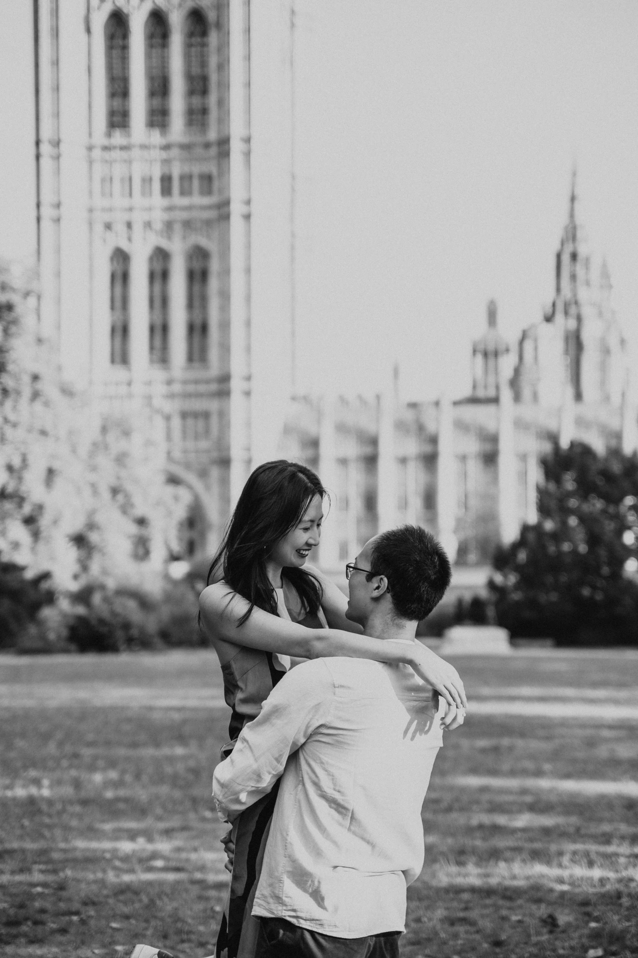 Black-and-white close portrait of the man holding his partner above the lawn in Victoria Tower Gardens, from their London couple photoshoot.